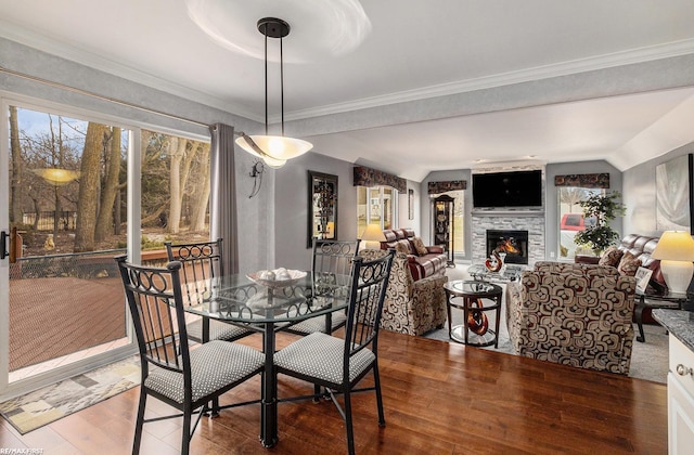 dining space with a glass covered fireplace, ornamental molding, and wood finished floors