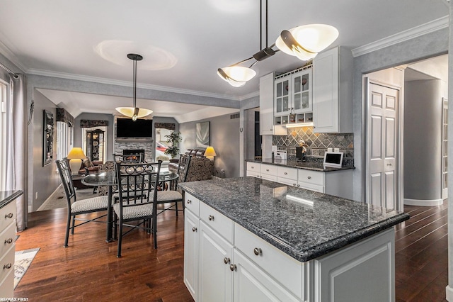 kitchen with crown molding, glass insert cabinets, dark wood-style floors, and open floor plan