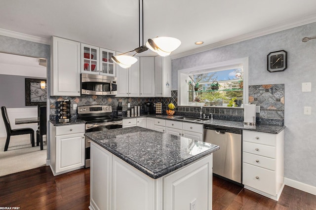 kitchen with dark wood finished floors, a sink, ornamental molding, stainless steel appliances, and backsplash