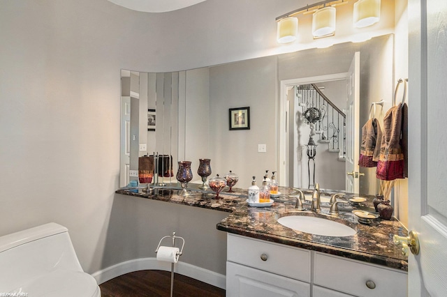 bathroom with toilet, vanity, baseboards, and wood finished floors