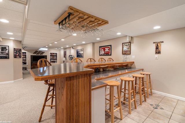 bar with recessed lighting, indoor wet bar, baseboards, and a paneled ceiling