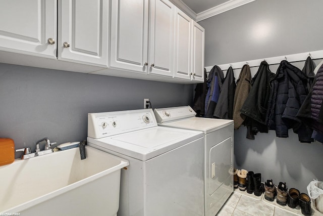 laundry area featuring light tile patterned floors, cabinet space, ornamental molding, a sink, and washer and clothes dryer