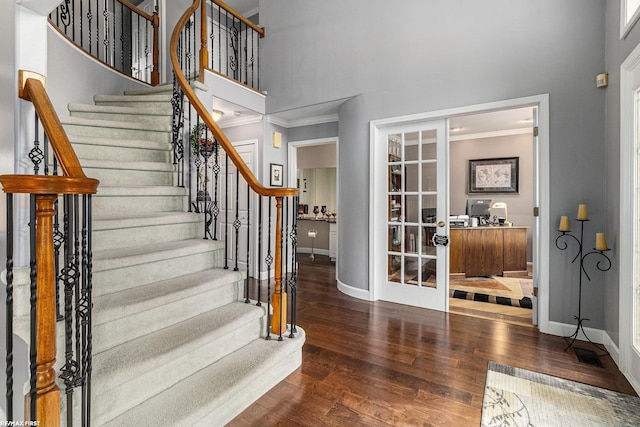 foyer with wood finished floors, french doors, baseboards, and ornamental molding