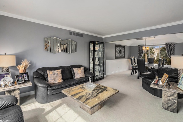 living room with carpet, a wainscoted wall, visible vents, an inviting chandelier, and crown molding