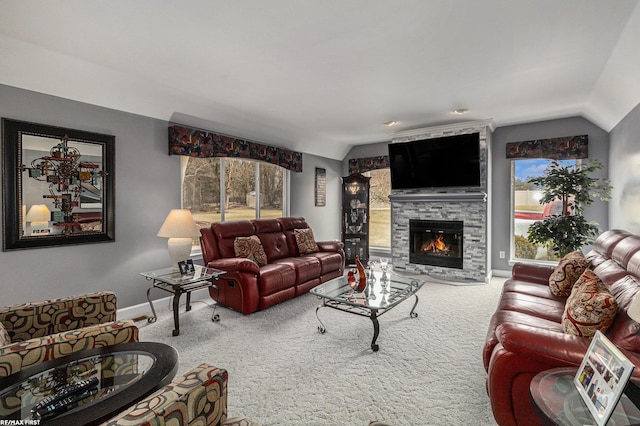 carpeted living room with baseboards, a large fireplace, plenty of natural light, and vaulted ceiling