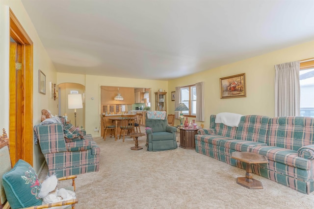 carpeted living room featuring plenty of natural light and arched walkways