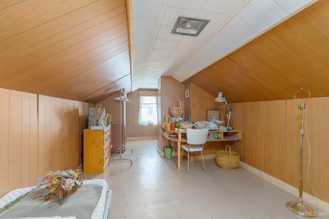 additional living space featuring baseboards, wood walls, and vaulted ceiling