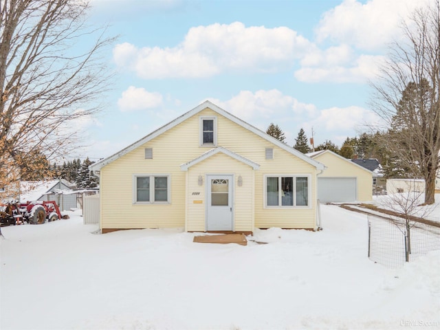 bungalow featuring a detached garage, fence, and an outdoor structure