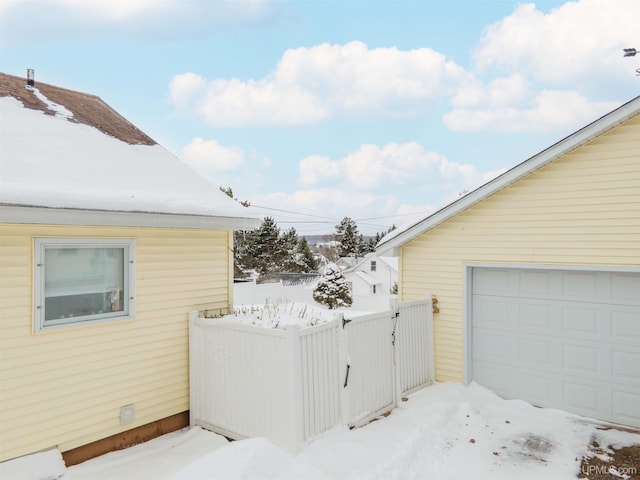 view of snowy exterior featuring a garage and fence