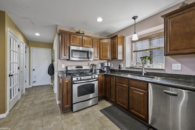 kitchen featuring dark stone countertops, recessed lighting, a sink, appliances with stainless steel finishes, and decorative light fixtures