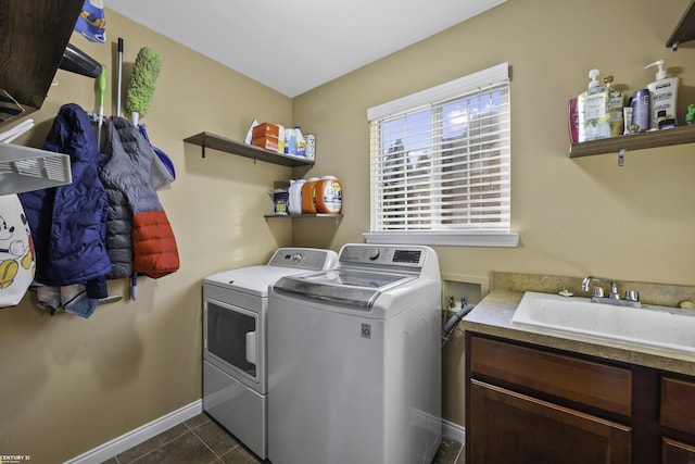 laundry area featuring dark tile patterned flooring, baseboards, separate washer and dryer, cabinet space, and a sink