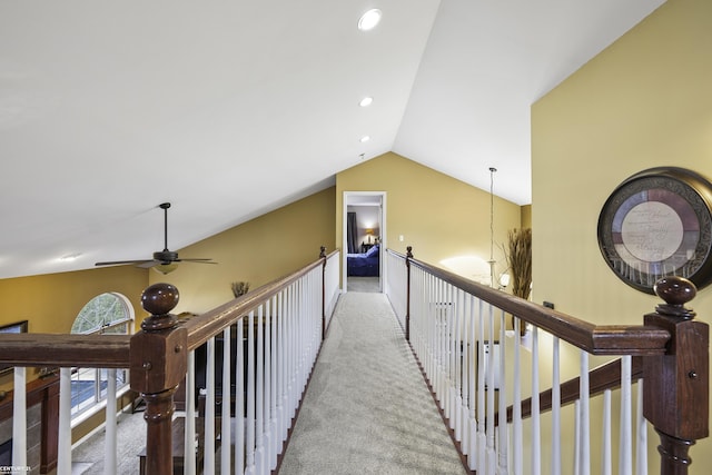 hallway with an upstairs landing, carpet flooring, and lofted ceiling