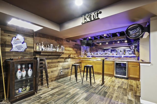 bar with wine cooler, wooden walls, wet bar, and wood finished floors