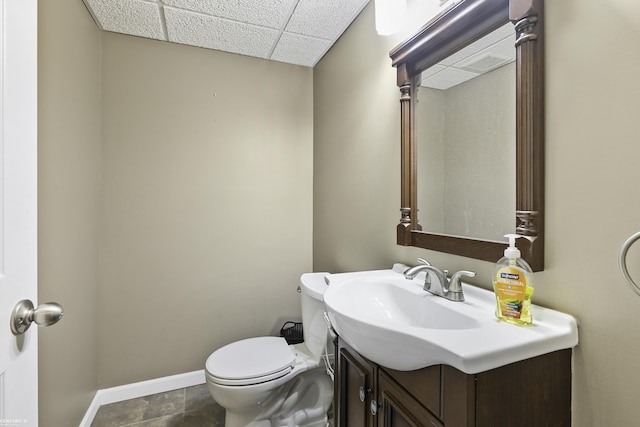 bathroom featuring toilet, vanity, a paneled ceiling, and baseboards