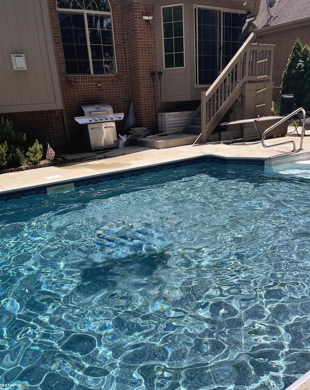 pool featuring area for grilling, stairs, and a patio