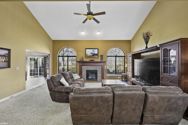 carpeted living room with high vaulted ceiling, a ceiling fan, baseboards, and a tile fireplace