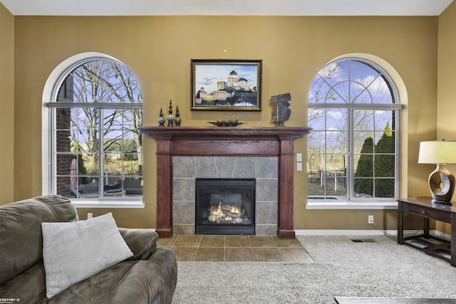 carpeted living area with baseboards and a tiled fireplace