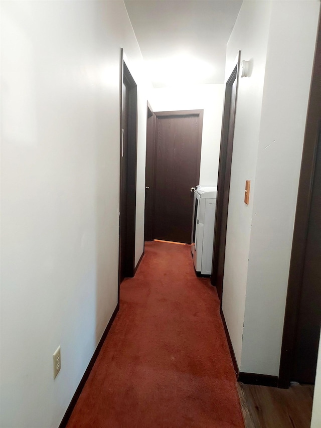 hall with washer / dryer, baseboards, and light carpet