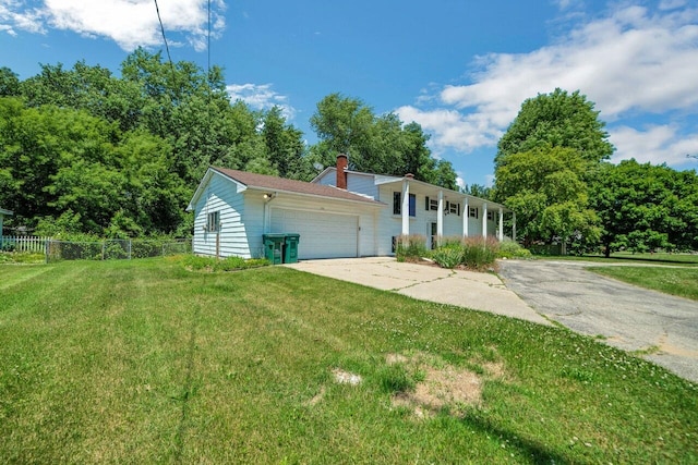 view of front facade featuring a front lawn, fence, concrete driveway, a chimney, and a garage