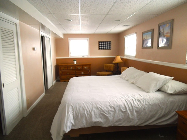 bedroom with a paneled ceiling, carpet floors, and baseboards