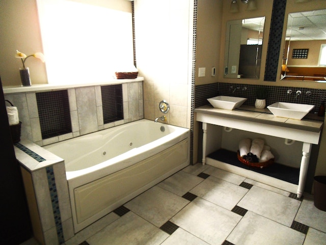 bathroom with tile patterned flooring, a jetted tub, and a sink