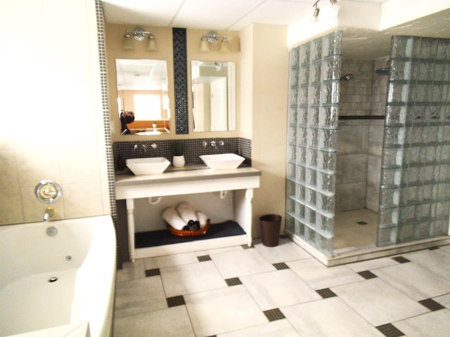 bathroom featuring a sink, backsplash, walk in shower, and a whirlpool tub