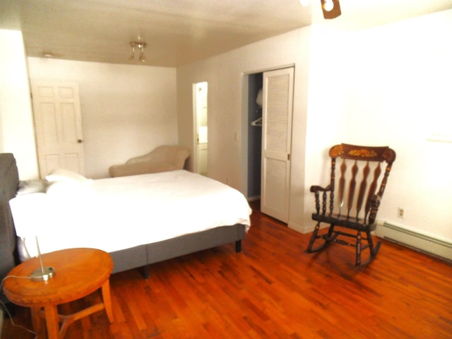 bedroom featuring baseboard heating and wood finished floors