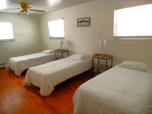 bedroom featuring multiple windows, wood finished floors, and ceiling fan