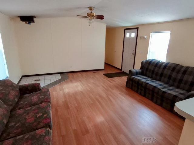 living area featuring light wood-style flooring, a ceiling fan, and vaulted ceiling