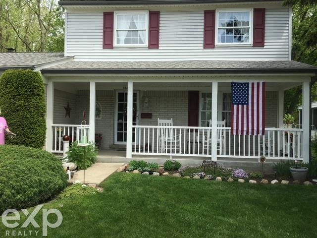 view of front facade featuring brick siding, covered porch, and a front lawn