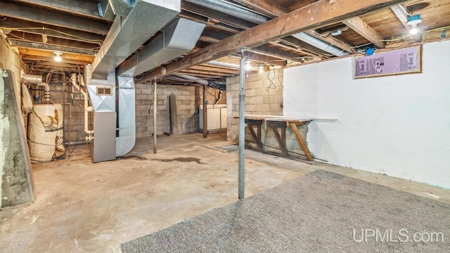 unfinished basement with water heater, heating unit, washer / clothes dryer, and visible vents