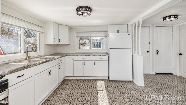 kitchen with white cabinets, range with electric stovetop, freestanding refrigerator, and a sink