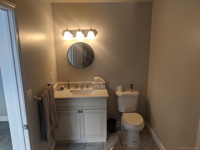 bathroom with toilet, vanity, marble finish floor, and baseboards