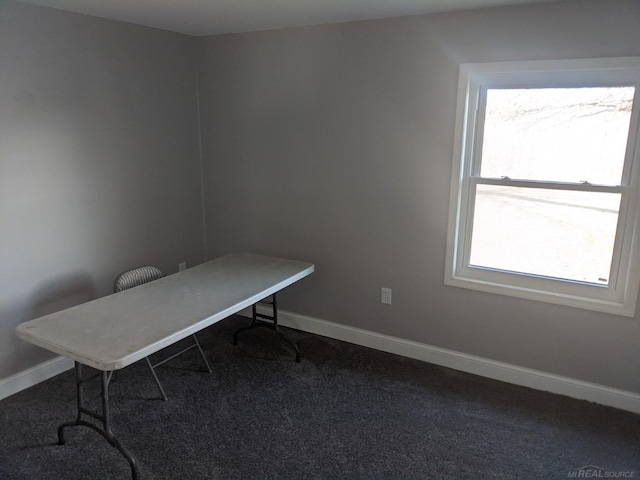 unfurnished office with baseboards and dark carpet