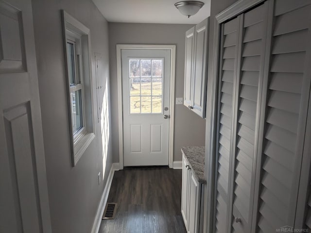 doorway featuring dark wood-style floors, visible vents, and baseboards