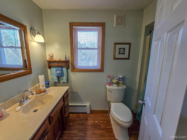 bathroom featuring a baseboard heating unit, baseboards, toilet, wood finished floors, and vanity