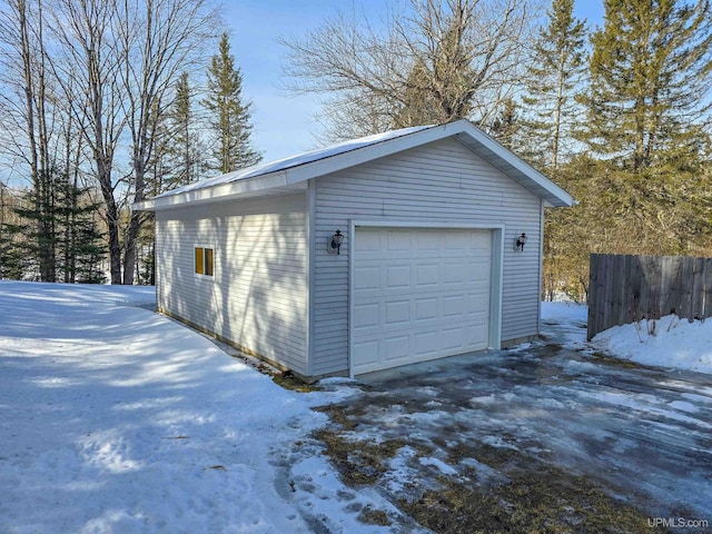 snow covered garage with fence and a garage