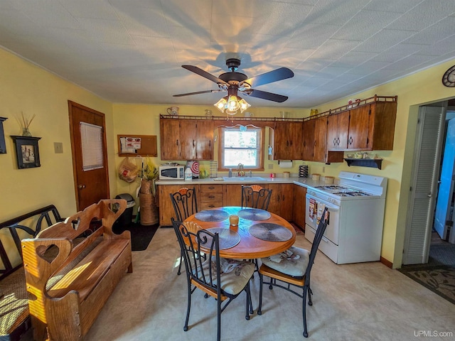 kitchen featuring brown cabinetry, white appliances, light countertops, and a sink