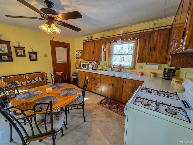 kitchen with brown cabinets, white appliances, light countertops, and a sink