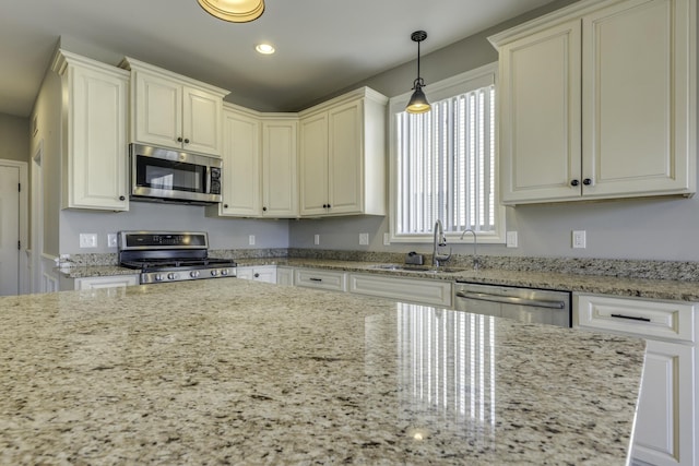 kitchen with a sink, stainless steel appliances, light stone countertops, and hanging light fixtures