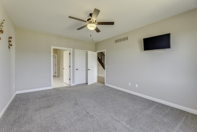 unfurnished bedroom with a ceiling fan, carpet flooring, baseboards, and visible vents