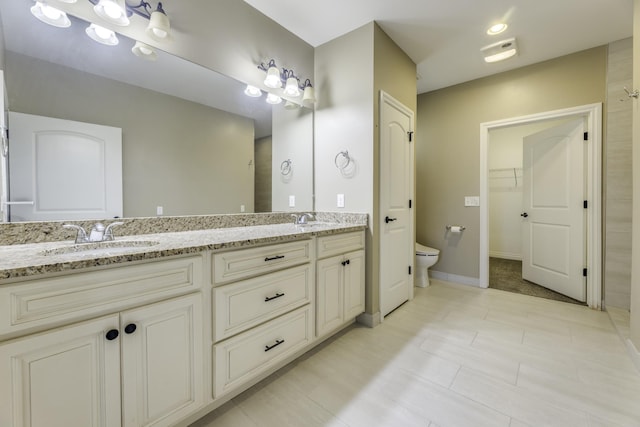 full bathroom with double vanity, toilet, baseboards, and a sink