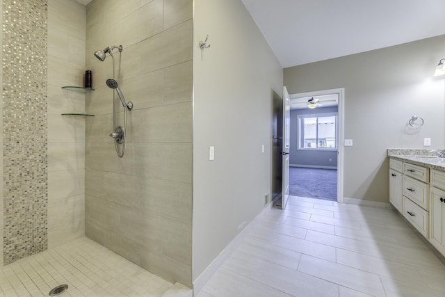 bathroom with tile patterned floors, baseboards, vanity, and a tile shower