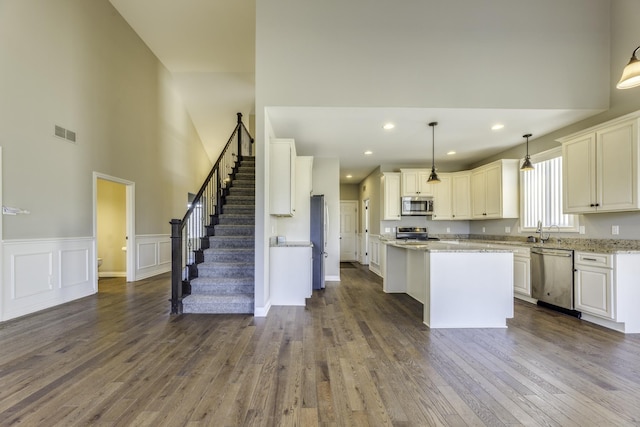 kitchen with visible vents, a kitchen island, dark wood finished floors, a wainscoted wall, and stainless steel appliances