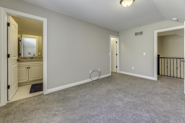 unfurnished bedroom featuring light carpet, visible vents, baseboards, and vaulted ceiling