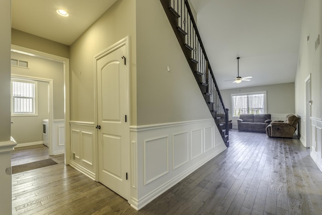 corridor with stairway, a decorative wall, visible vents, and hardwood / wood-style flooring