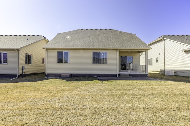 rear view of house with a yard, cooling unit, and a shingled roof