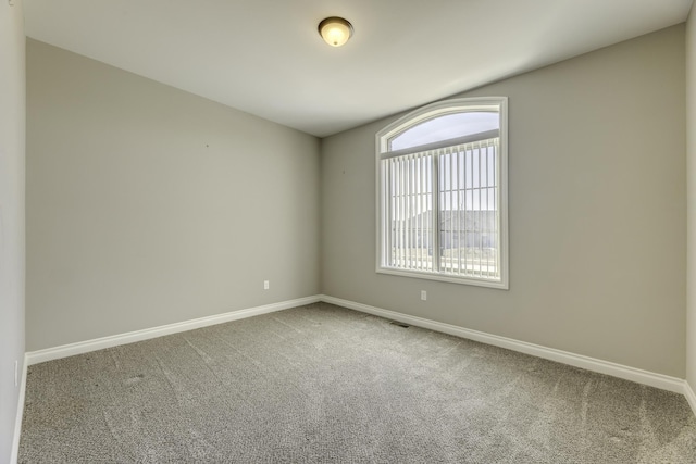 carpeted spare room featuring visible vents and baseboards