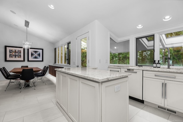 kitchen featuring visible vents, a kitchen island, a sink, white cabinets, and lofted ceiling with skylight