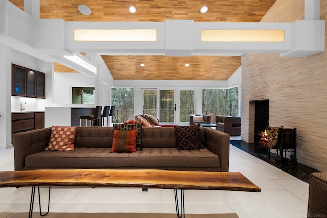 living area with high vaulted ceiling, recessed lighting, a lit fireplace, light tile patterned flooring, and wood ceiling